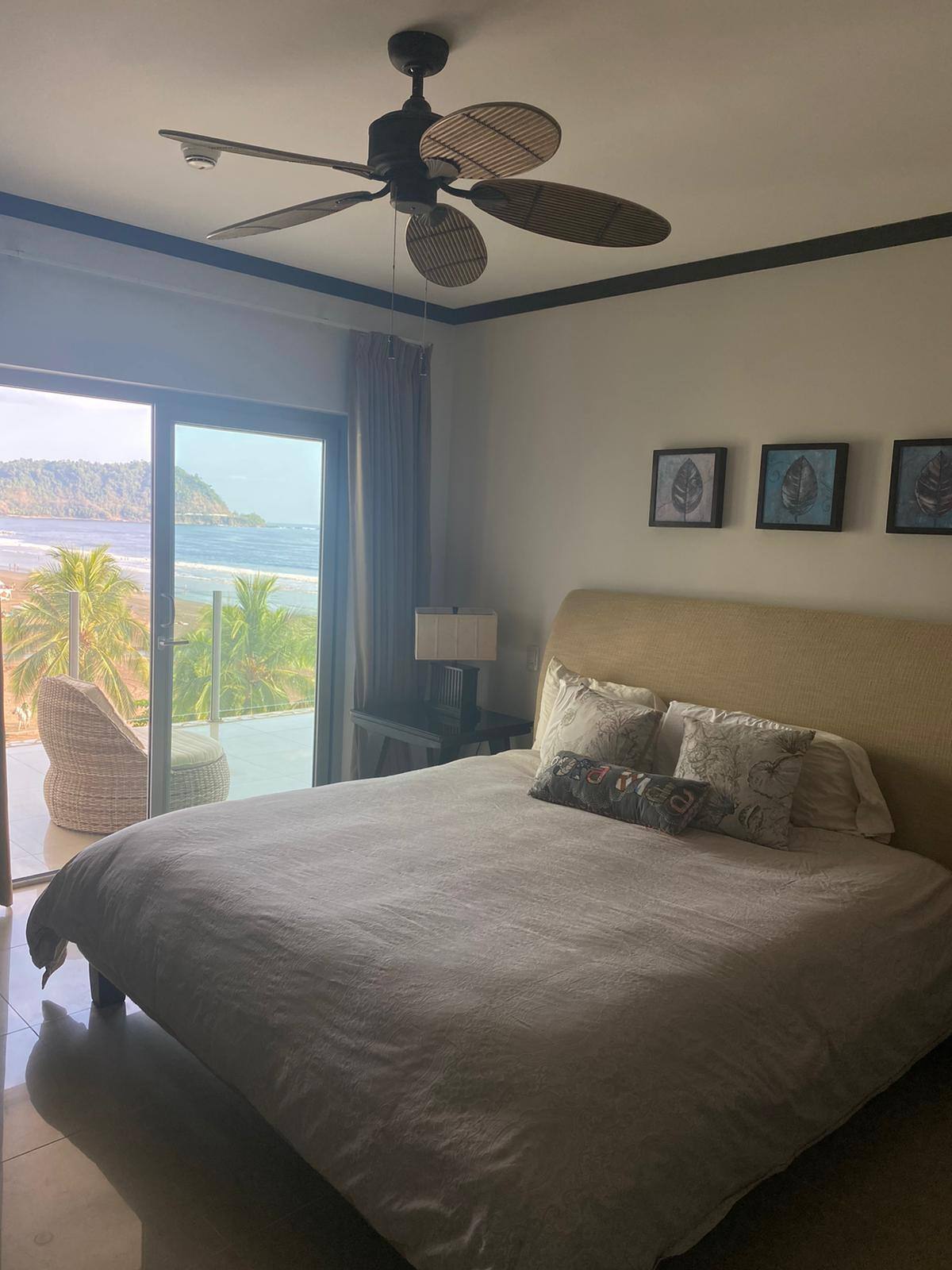 Primary bedroom with sliding doors opening toward an ocean-view balcony